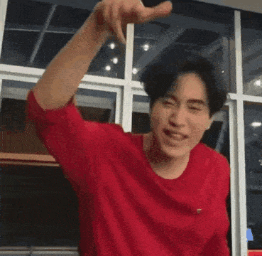 a man in a red shirt is pointing at the camera .