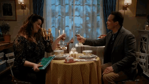 a man and a woman are sitting at a table toasting