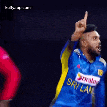 a man in a blue and yellow jersey is giving a thumbs up while standing on a field .