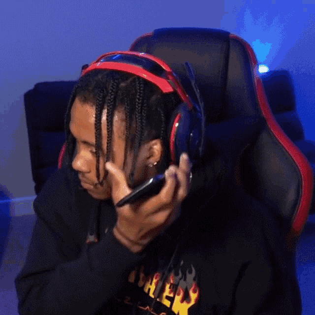 a man wearing headphones and a thrasher sweatshirt is talking on a cell phone