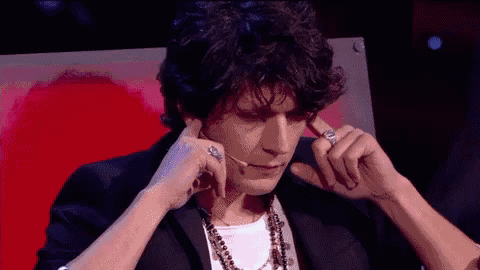 a man with rings on his fingers is covering his ears with his hands .