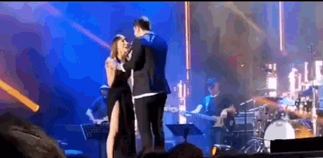 a man and a woman are dancing on a stage in front of a band .