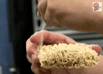 a person is holding a piece of ramen noodles in their hand .