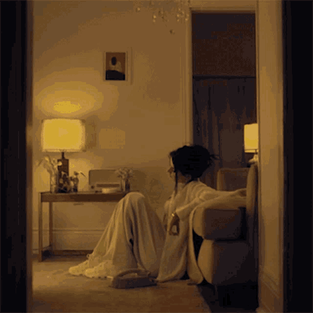 a woman sits on a couch in a dark room
