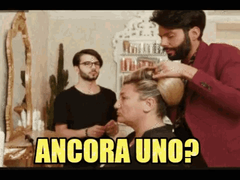 a man is cutting a woman 's hair with the words ancora uno written on the bottom