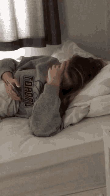 a girl wearing a toronto sweatshirt laying on a bed