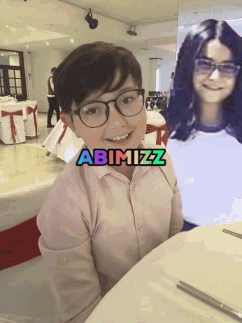 a boy wearing glasses sits at a table next to a picture of a girl with abimizz written on it