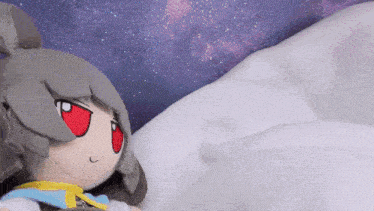 a stuffed animal with red eyes is laying on a bed .