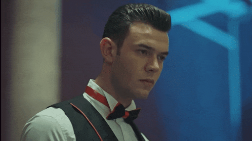 a man in a tuxedo and bow tie looks down at something