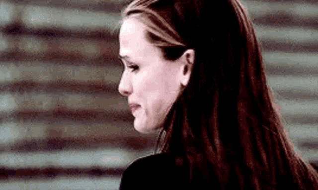 a close up of a woman 's face with long hair crying .