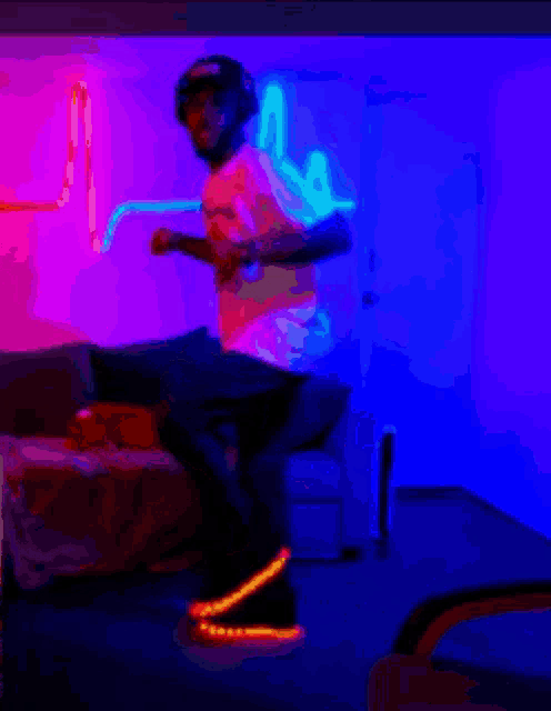 a man is dancing in a living room with neon lights behind him