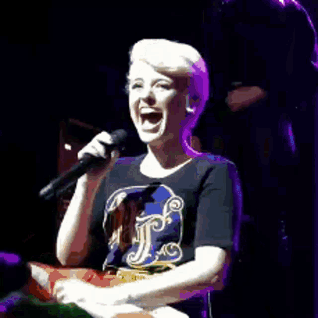 a woman is laughing while singing into a microphone on stage .
