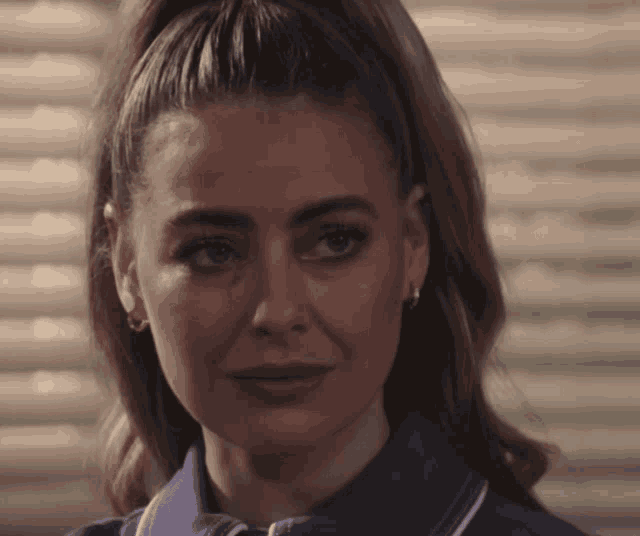 a woman with a ponytail is wearing a blue shirt