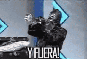 a man in a mask is holding a gun and saying y fuera .