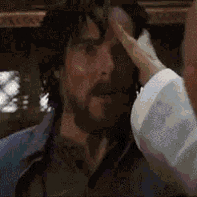 a man with a beard is scratching his forehead .