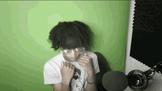 a person wearing a t-shirt that says ' jordan ' on it is sitting in front of a microphone