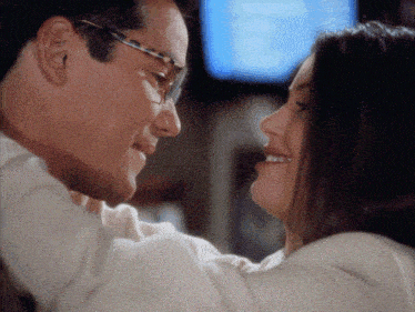 a man wearing glasses is holding a woman in his arms