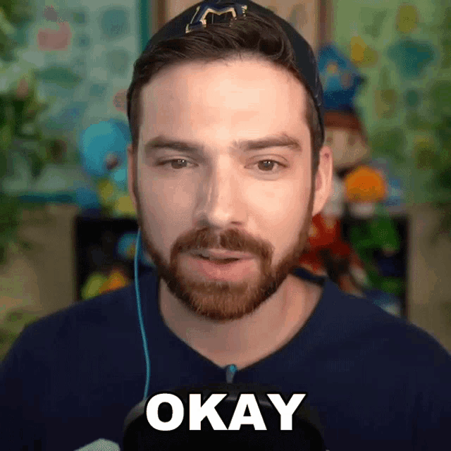 a man with a beard is wearing a hat and headphones and says okay