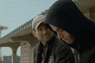 a man in a hooded jacket has a patch on his jacket that says ' roots ' on it