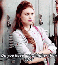 a woman is standing next to a man in front of lockers and talking to him .