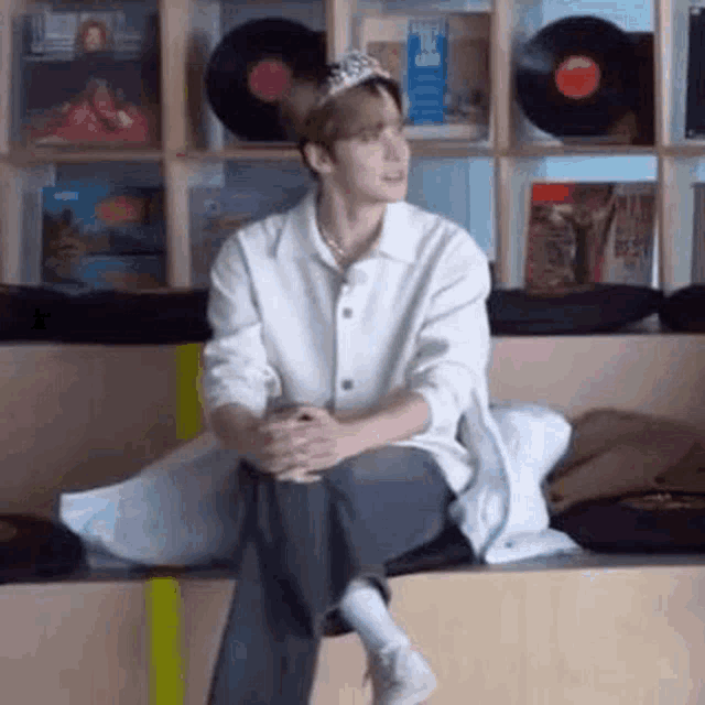 a man wearing a crown is sitting on a bench in front of a record shelf .