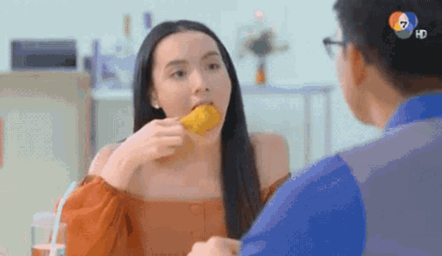 a woman is eating a corn on the cob while talking to a man .