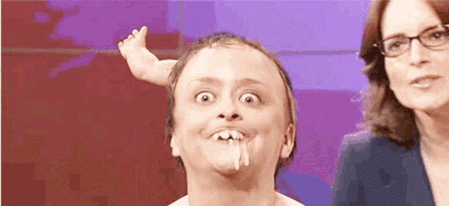 a man with a baby 's foot sticking out of his mouth and a woman behind him .