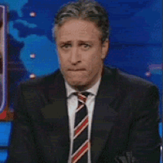 a man in a suit and tie is covering his mouth with his hands