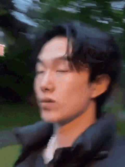 a blurry photo of a young man with his eyes closed .