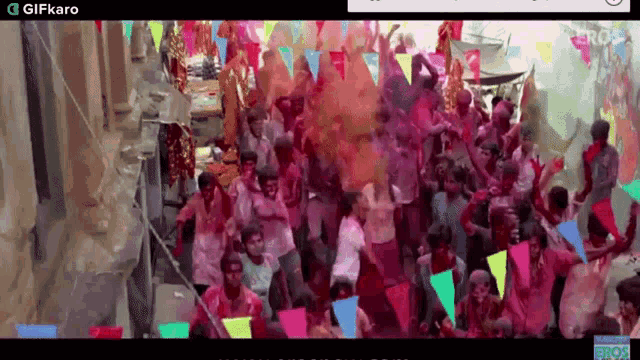 a large group of people are celebrating a festival with flags and powder .