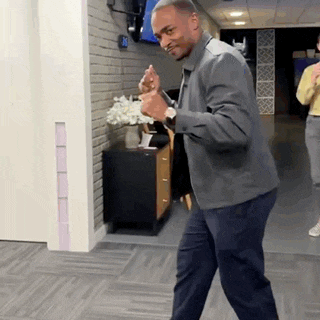 a man in a gray jacket is dancing in a hallway