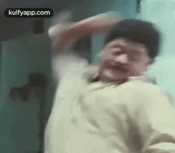 a man is dancing in a room with his arms outstretched and making a funny face .