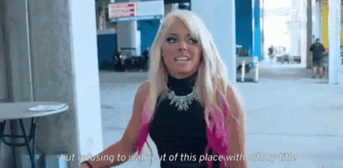 a woman with blonde hair is standing in a parking lot and talking to someone .