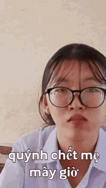 a girl wearing glasses and a white shirt is making a funny face in a classroom .