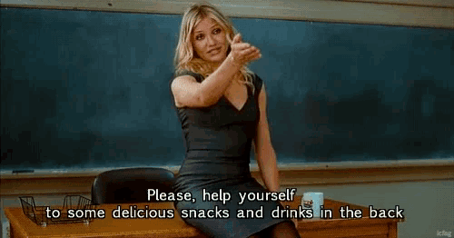 a group of people are sitting at desks in a classroom with a pitcher of water on the table