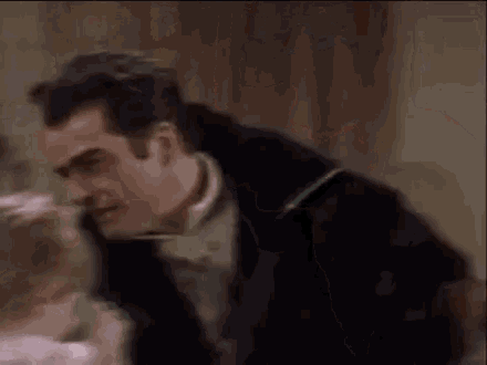 a man is kissing a little girl on the cheek while a woman looks on .