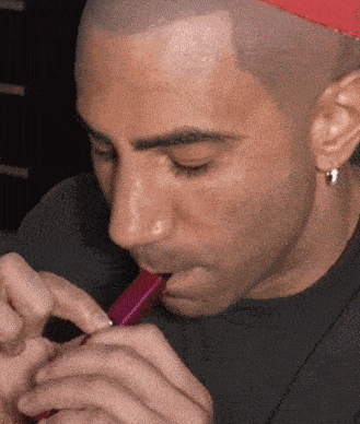 a man wearing a red hat is smoking a purple cigarette