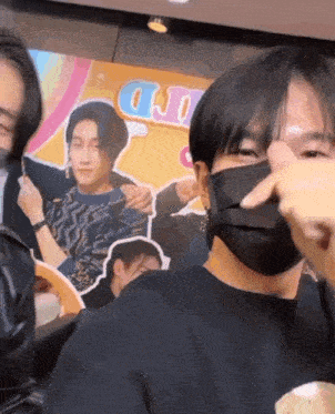 a man wearing a black mask is covering his face in front of a sign that says u.j.d.