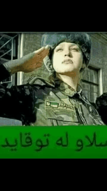a woman in a military uniform salutes in front of a building with arabic writing .