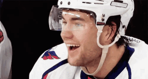 a close up of a hockey player wearing a helmet and smiling with his mouth open .