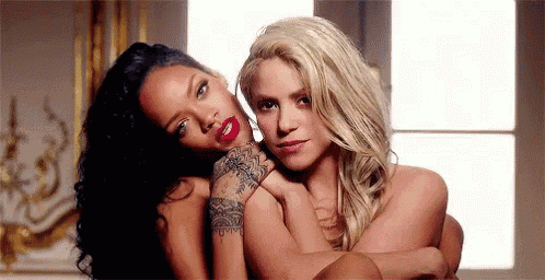 two naked women are hugging each other in front of a window in a room .