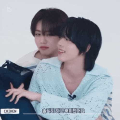 a couple of boys are hugging each other and one of them is wearing a blue shirt that says chimen