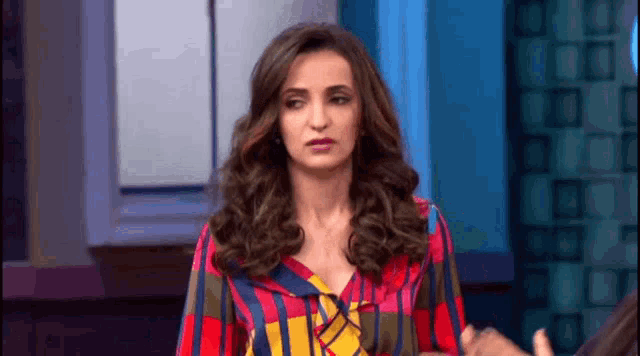 a woman in a colorful striped shirt is making a funny face on a television show .