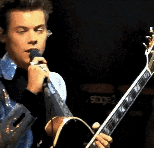 a man is singing into a microphone and playing a guitar .
