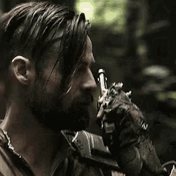 a close up of a man with a beard holding a gun .
