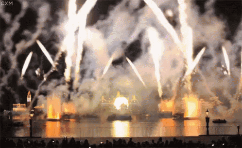 a crowd of people watching a fireworks display with cxm written on the bottom