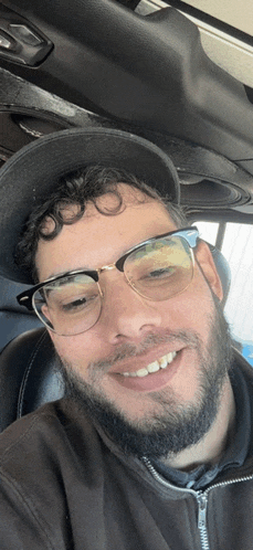 a man wearing glasses and a hat is smiling