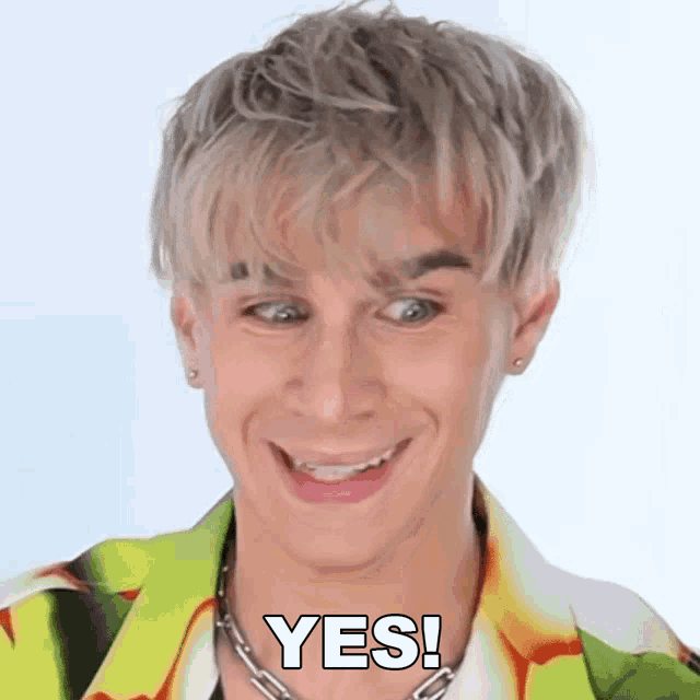 a young man with blonde hair is smiling and saying yes .