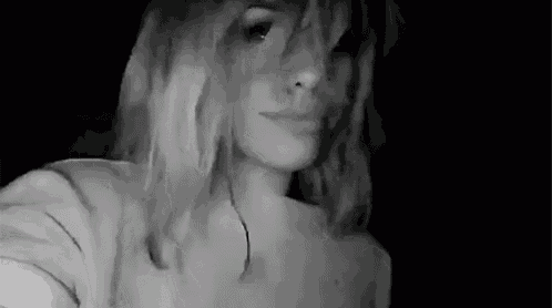 a black and white photo of a woman taking a selfie with her phone .