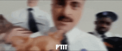 a man with a mustache is standing in front of a group of police officers and says ptit